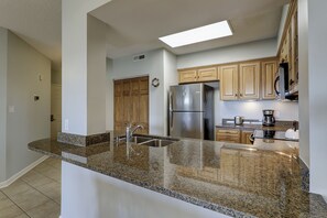 A modern kitchen with granite countertops, stainless steel appliances, and wooden cabinets.