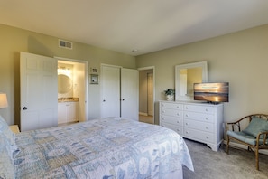 A bedroom with a bed, dresser, television, and a chair.