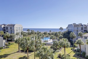 A resort with a pool, palm trees, and ocean views.