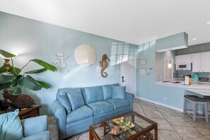 A living room with a blue sofa, a coffee table, and a large plant.