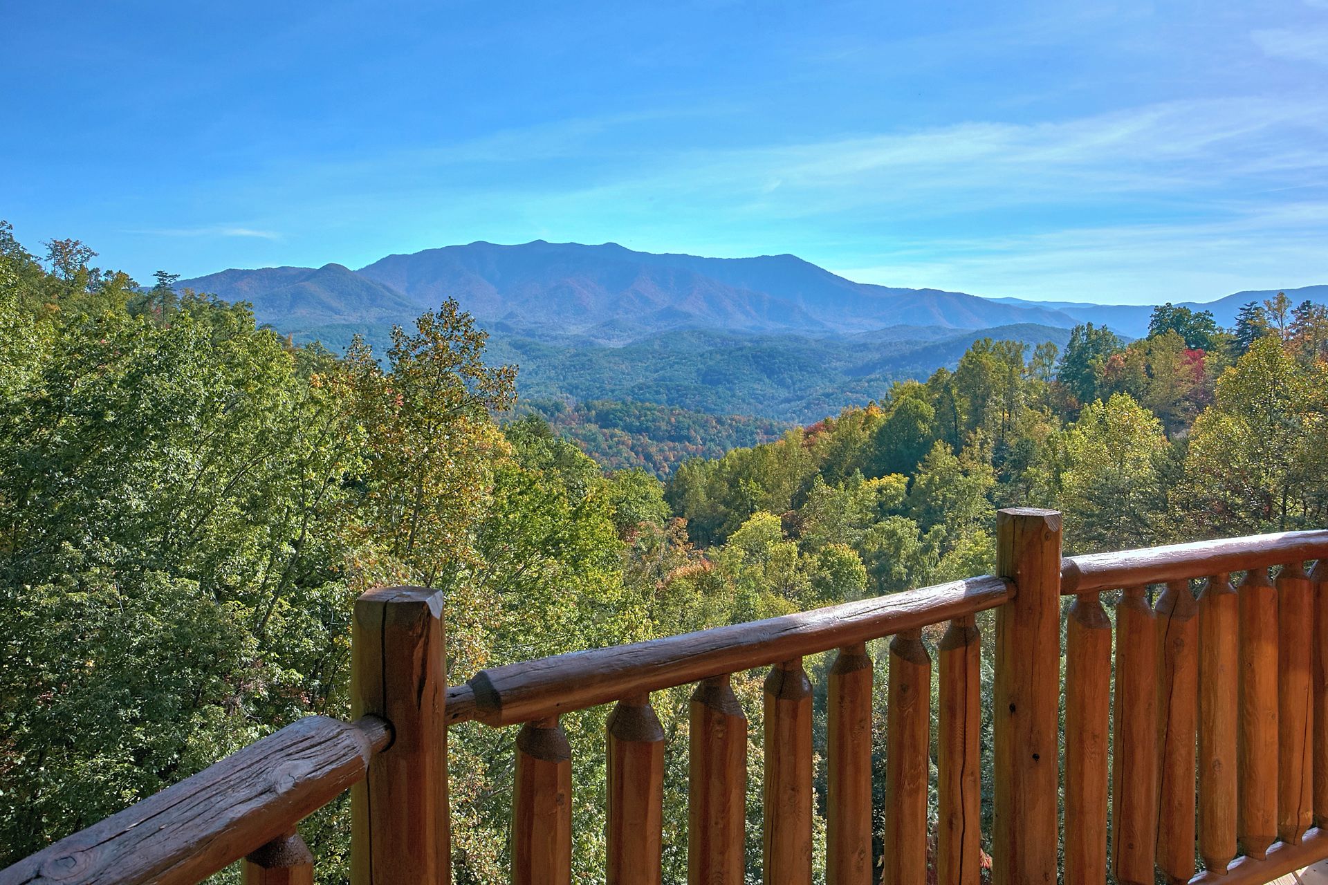 Barandilla de madera con vistas a un paisaje montañoso y un bosque denso.