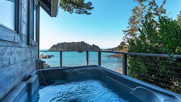 Un bain à remous avec vue sur la mer et une île rocheuse.