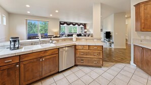A spacious kitchen with wooden cabinets, a dishwasher, and a large window providing natural light. - Quinn Creek - Gorgeous and Updated! Perfect Location in NW Bend, Pool Table, 20 Min To Bachelor! (Bend)