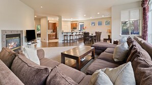 A spacious living room with a fireplace, a dining area, and a kitchen in the background. - Quinn Creek - Gorgeous and Updated! Perfect Location in NW Bend, Pool Table, 20 Min To Bachelor! (Bend)