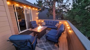 An outdoor patio with a sofa, chairs, and a fire table, surrounded by string lights. - Quinn Creek - Gorgeous and Updated! Perfect Location in NW Bend, Pool Table, 20 Min To Bachelor! (Bend)