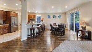 A spacious kitchen with a central island, wooden bar stools, and a dining area with a large table and chairs. - Quinn Creek - Gorgeous and Updated! Perfect Location in NW Bend, Pool Table, 20 Min To Bachelor! (Bend)