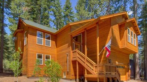 A wooden cabin with a porch, a staircase, and a flag.