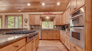 A spacious kitchen with wooden cabinets, a granite countertop, a stainless steel stove, and a large oven.