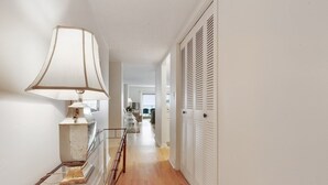 Un pasillo con una lámpara, una mesa de vidrio y un conjunto de puertas blancas con listones.
