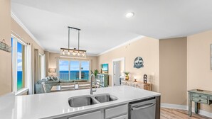 A modern kitchen with a large island, double sink, and built-in appliances. - GULF FRONT CONDO! SLEEPS UP TO 6! (Panama City Beach)