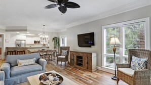 A spacious living room with a sofa, a coffee table, and a dining area with a chandelier.