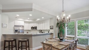 A modern kitchen with white cabinets, stainless steel appliances, and a large island with stools.