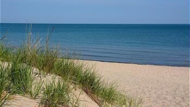 Une plage avec une eau d’un bleu limpide et du sable fin.
