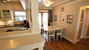 A kitchen with white cabinetry, a dining table with chairs, and a clock on the wall. - Peaceful Boise Bungalow, Short Drive to Downtown! (Boise)