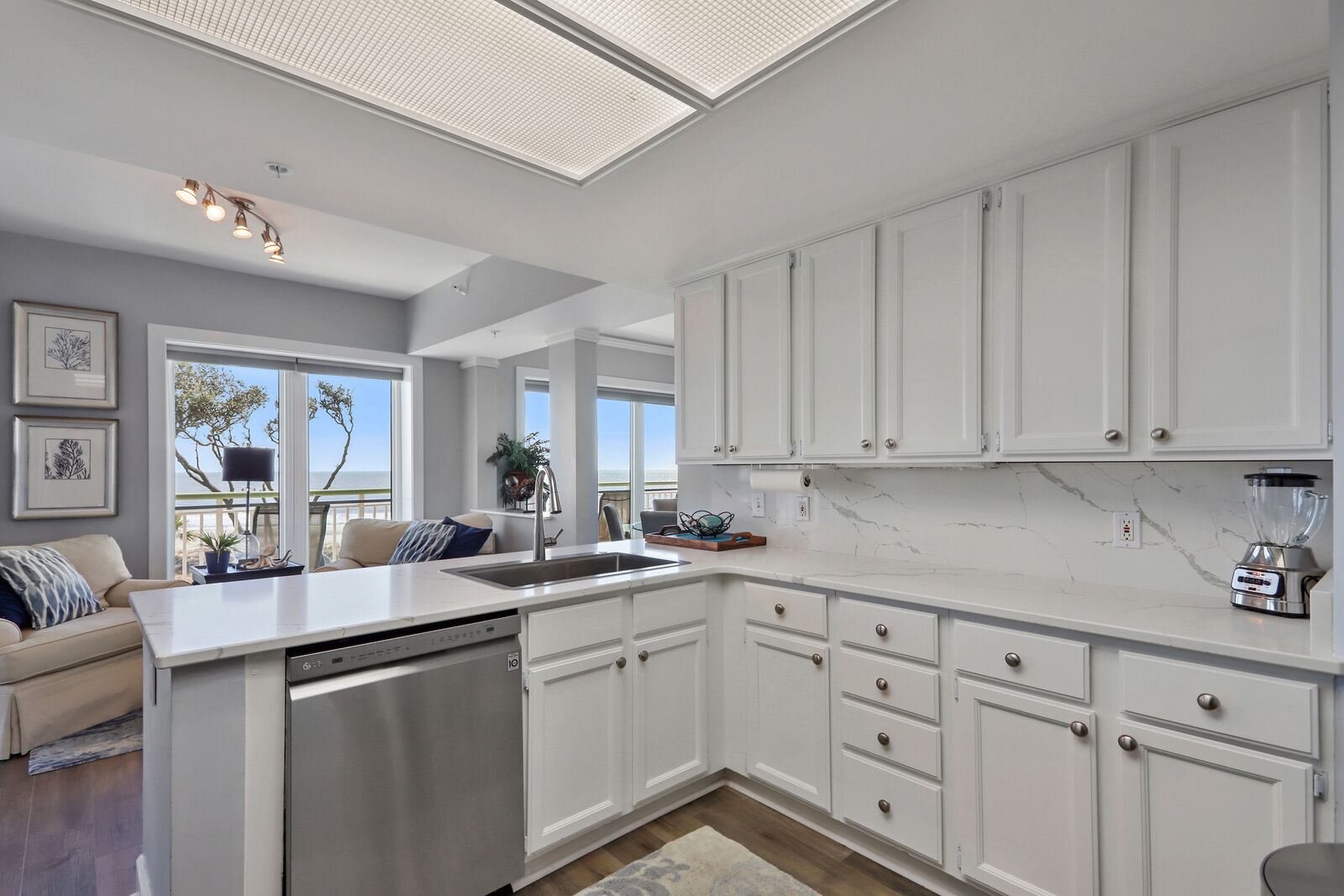A modern kitchen with white cabinetry, a built-in dishwasher, and a large island with a sink.