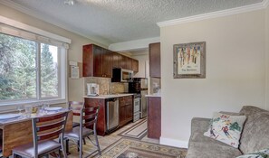 A kitchen with wooden cabinets, stainless steel appliances, and a dining area with a table set for four.