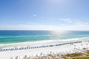 A beach with white sand, a clear blue sky, and the ocean.