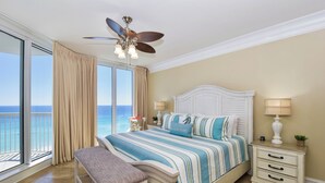 A bedroom with a bed, a nightstand, a bench, a ceiling fan, and a view of the ocean. - Updated, luxurious beachfront condo w/ Tempur-Pedic King in Master! 🌊 (Destin)