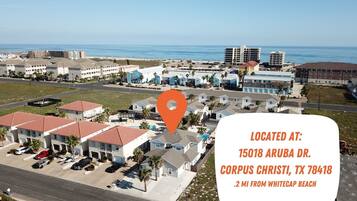 Vista aérea de Corpus Christi, Texas, que destaca una zona residencial con edificios de varios pisos, una vista despejada del océano y una carretera que lleva a la playa.