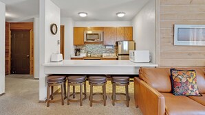 A compact kitchen with wooden cabinets, a white countertop, and a stainless steel refrigerator. - Affordable Ski Condo with Rustic Charm: Ski-In Access, Close to Main St dba12 (Breckenridge)