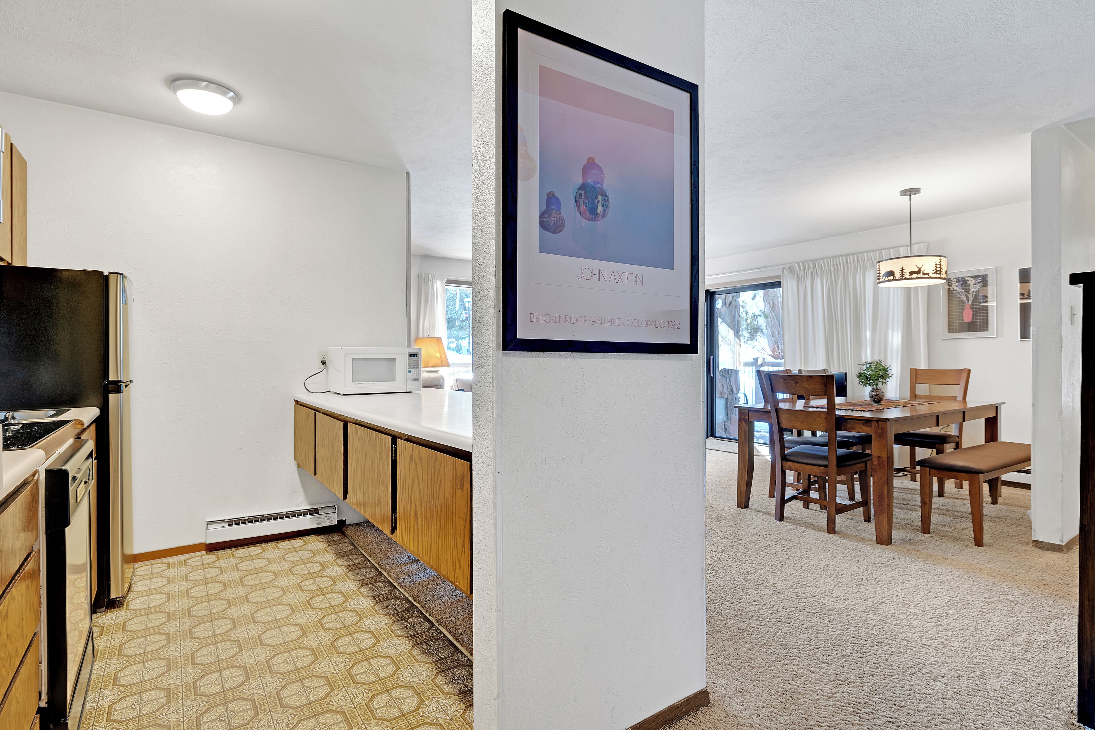 A modern kitchen with a built-in oven, a microwave, and a dishwasher. There is a dining area with a wooden table and chairs.