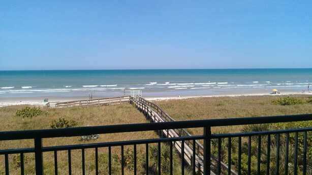 A beach view with a wooden boardwalk leading to the shore. - Direct Ocean 3 bed, 3 1/2 bath (Cocoa Beach)