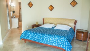 A bedroom with a bed, nightstands, a mirror, and a bathroom visible in the background. - Direct Ocean 3 bed, 3 1/2 bath (Cocoa Beach)