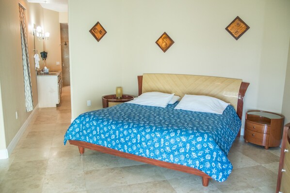 Un dormitorio con cama, mesitas de noche, un espejo y un baño a la vista.