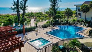 A pool area with a view of the sea, surrounded by trees and a building.