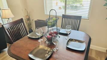 A dining table set with plates, glasses, and a fruit basket.