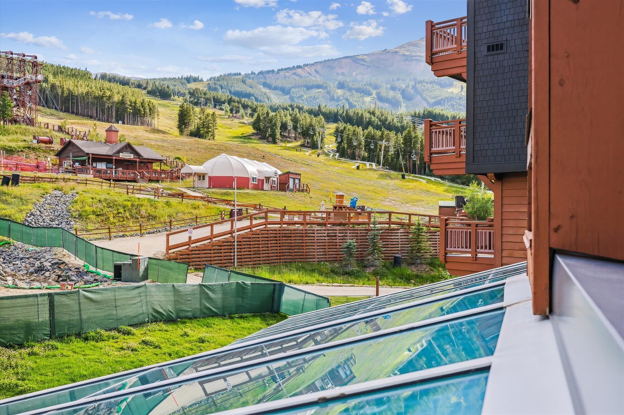 Un hotel con vistas a un paisaje montañoso, un telesilla y una zona de piscina.