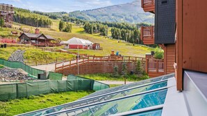 A hotel with a view of a mountainous landscape, a ski lift, and a pool area.