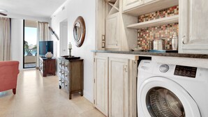 Een wasserij met een wasmachine, kasten en een betegelde spatwand.
