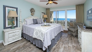 A bedroom with a bed, bedside tables, a ceiling fan, a view of the ocean, and a balcony with a chair. - GULF VIEWS IN A  PREMIER RESORT!! GREAT RATES! (Destin)