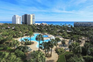 Un resort con piscina central, palmeras y vistas a la playa.