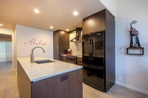 A modern kitchen with a built-in island, stainless steel appliances, and a decorative wall piece.