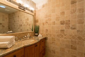 A bathroom with a marble sink, wooden cabinets, a large mirror, and beige tiled walls. - Special Offer Pool home Casa Paraiso Luxury 3 BR Home (Scottsdale)