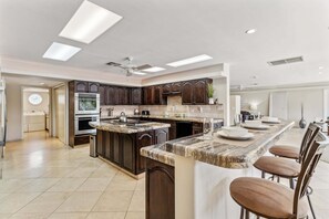 Una cocina moderna con gabinetes de madera oscura, encimera de granito y horno empotrado.