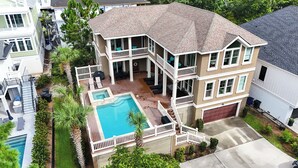 Une maison à deux étages avec une piscine, un patio couvert et un garage.