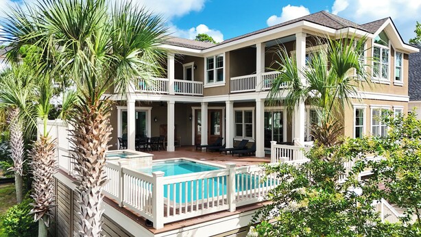Une maison à deux étages dotée d’une piscine, de balcons et d’un patio couvert.