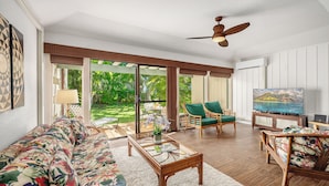 A spacious living room with a sofa, chairs, a coffee table, and a television. - Manualoha 1102 Perfect AC throughout By Suite Paradise (Koloa)