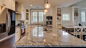 A kitchen with granite countertops, stainless steel appliances, and pendant lighting. - 77A Dune-Awesome Ocean Views, Pool, Spa, Pool Table, Elevator & Much More (Hilton Head Island)