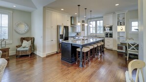A spacious kitchen with a large island, white cabinetry, and a dining area with bar stools. - 77A Dune-Awesome Ocean Views, Pool, Spa, Pool Table, Elevator & Much More (Hilton Head Island)