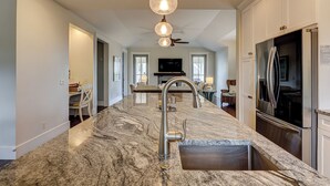 A kitchen with a marble countertop, stainless steel appliances, and a ceiling fan. - 77A Dune-Awesome Ocean Views, Pool, Spa, Pool Table, Elevator & Much More (Hilton Head Island)