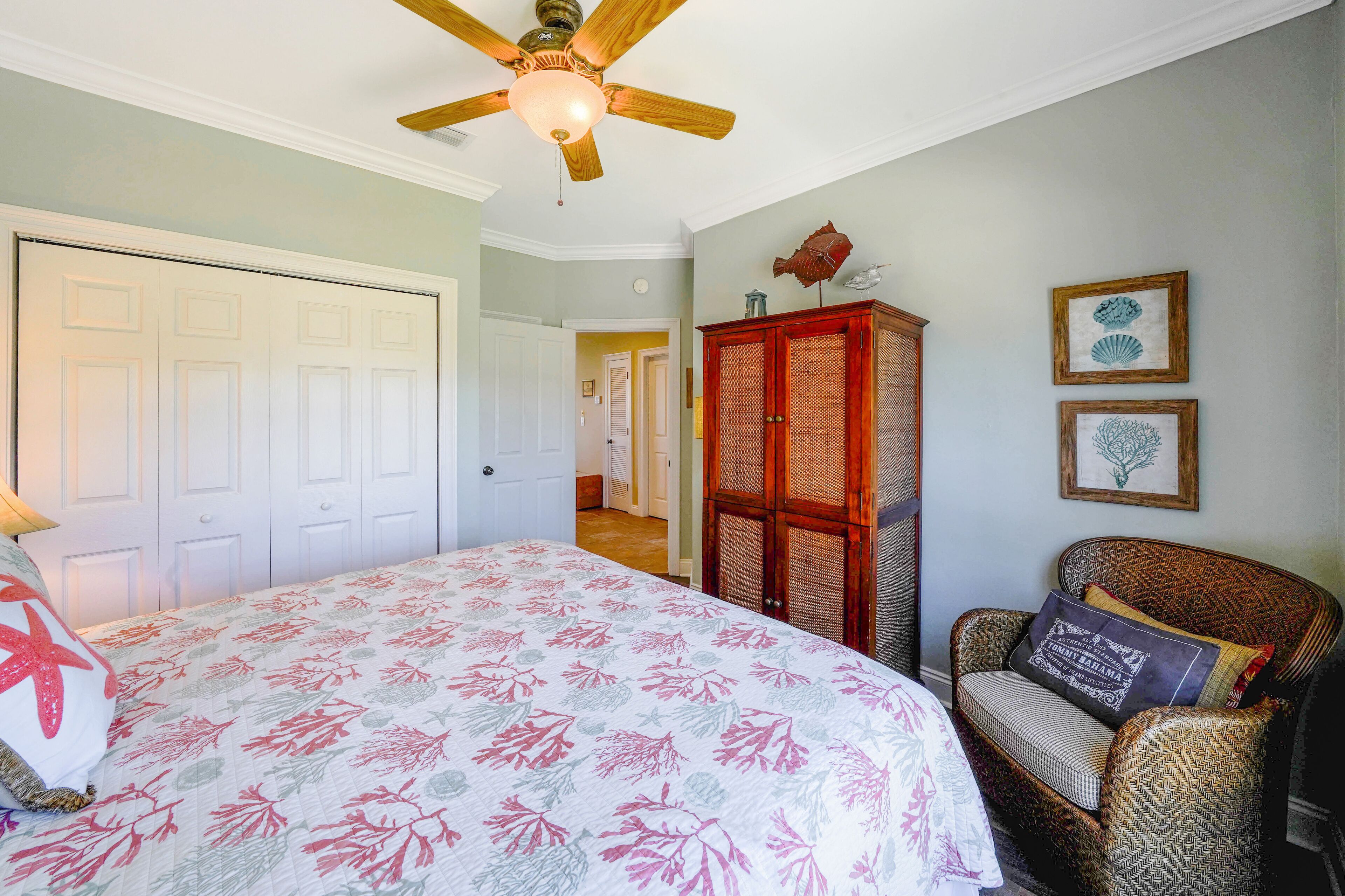 A bedroom with a bed, a ceiling fan, a wardrobe, and a chair.