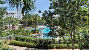 Un resort con piscina, palmeras y una cerca blanca.