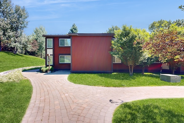 Situated on a curved pathway, this building features a modern design with large windows and a minimalist aesthetic.