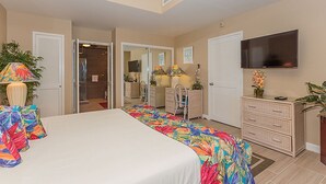 Une chambre d’hôtel avec un grand lit, un téléviseur fixé au mur, un bureau avec une chaise et une commode.