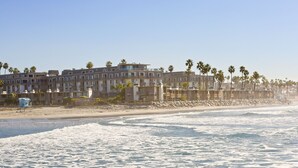 A beachfront hotel with multiple floors, balconies, and palm trees. - Awesome Sunset Ocean Views, Huge deck with Beautiful Ocean/Harbor Views, G317 North Coast Village (Oceanside)