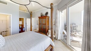 Une chambre spacieuse avec un grand lit, une armoire en bois et un balcon aménagé avec du mobilier d’extérieur.